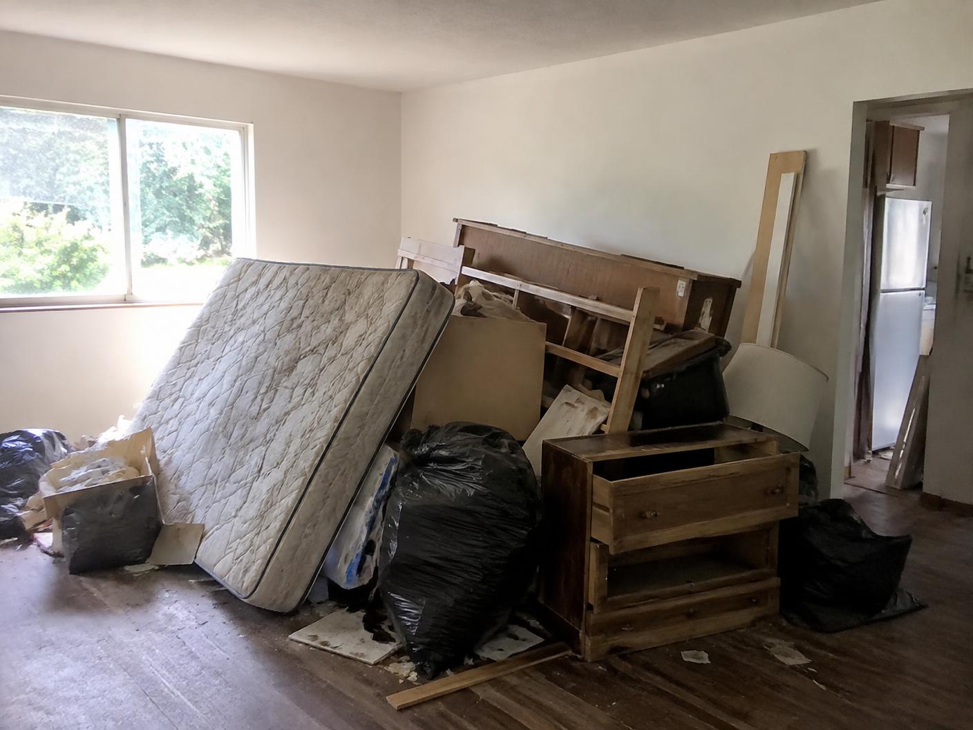 Pile of left-behind furniture and bags in an empty rental unit